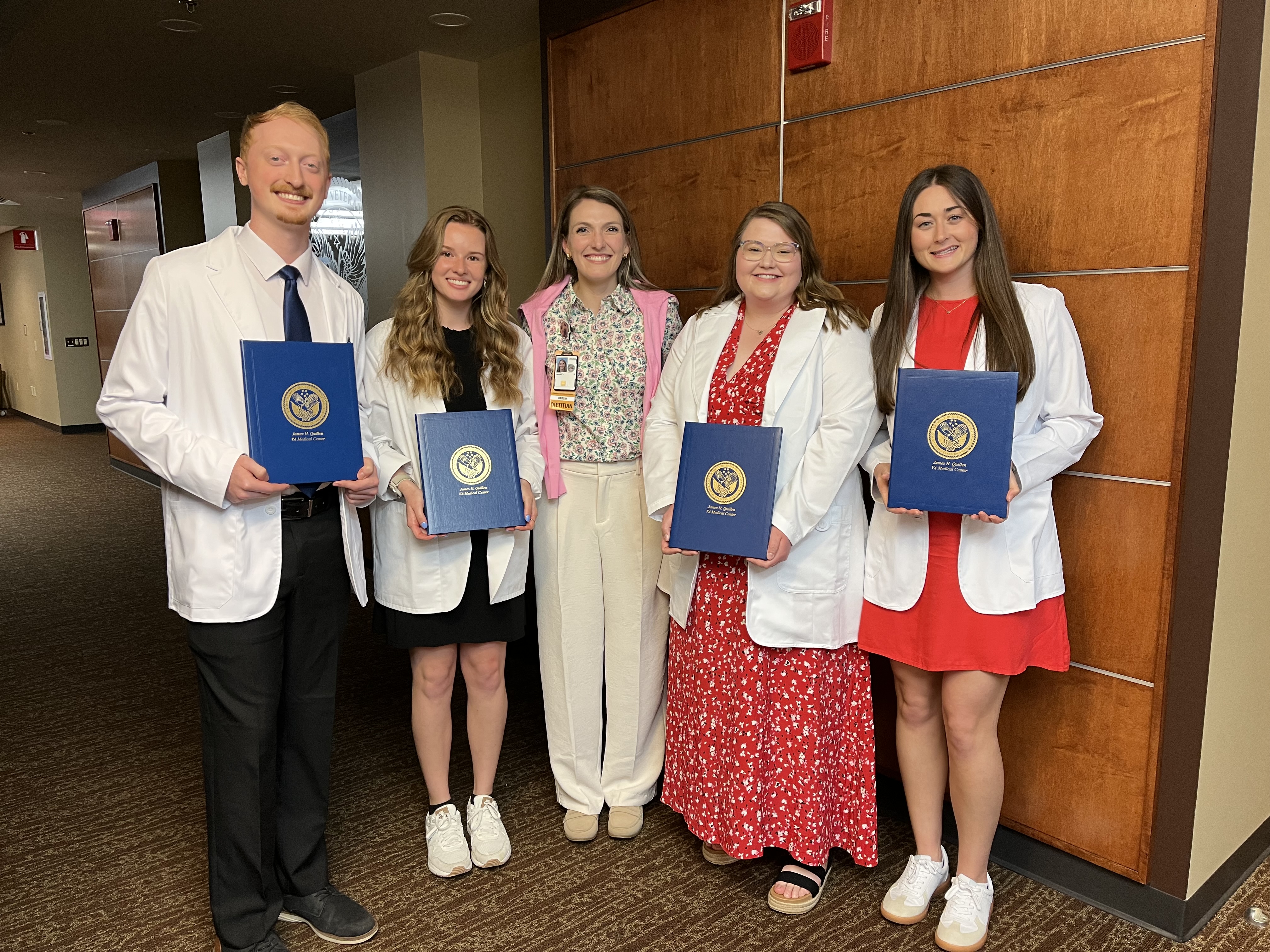 five people standing together with graduation certificates